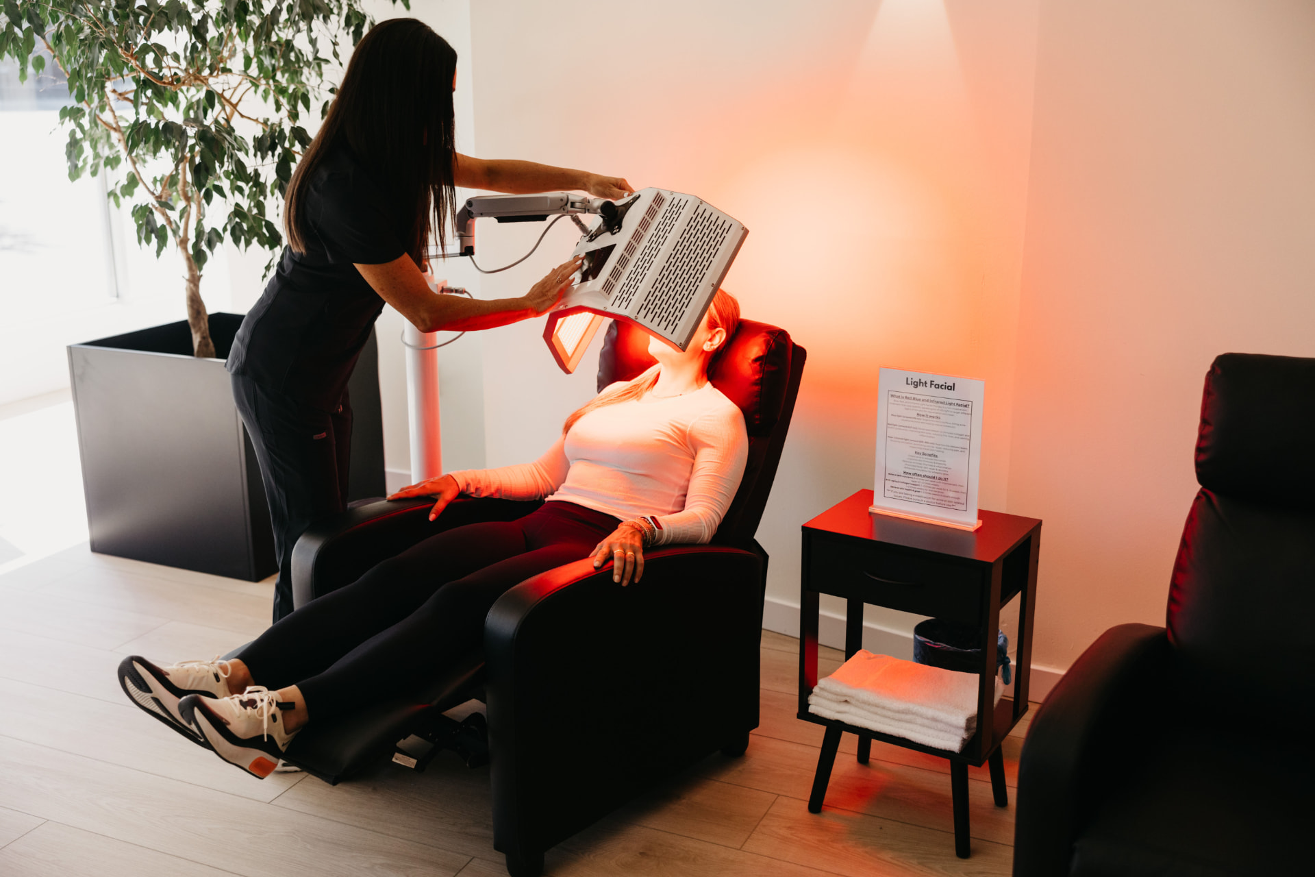 A Recharge team member positioning a light therapy panel over a member for a light facial